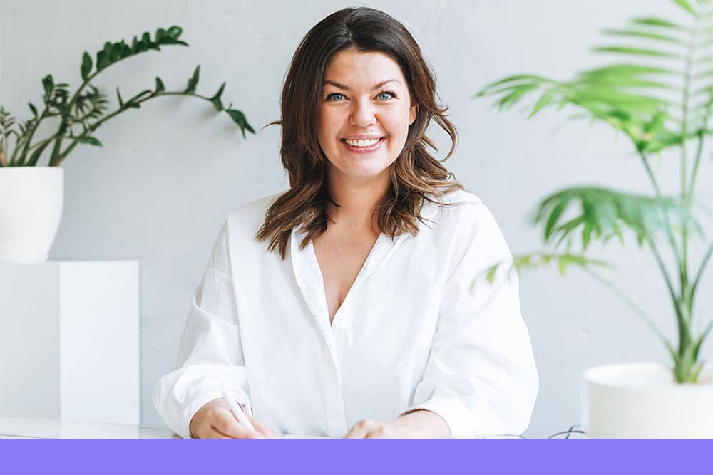 smiling woman in a white shirt sitting at a desk